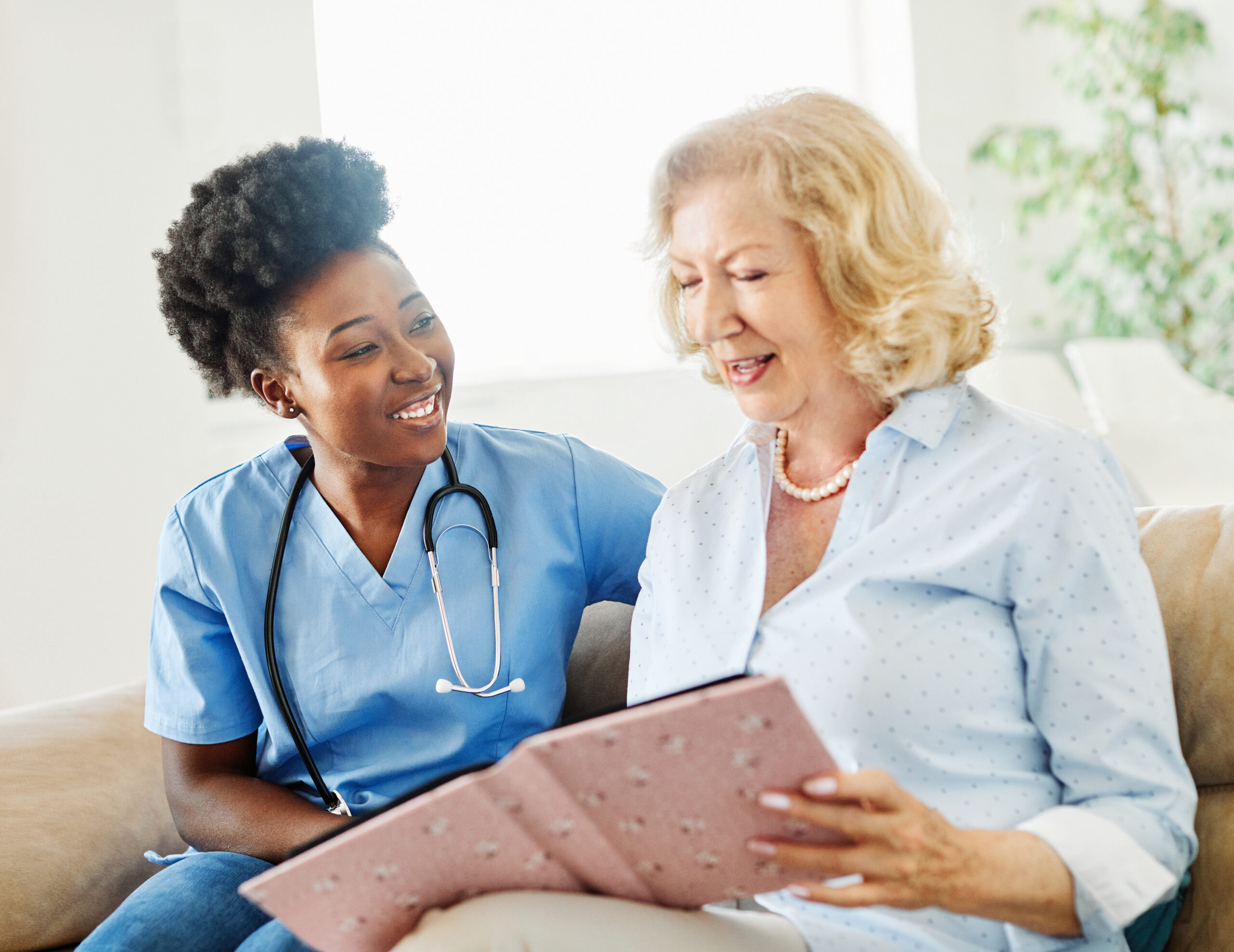 Doctor or nurse caregiver with senior woman looking at photo album